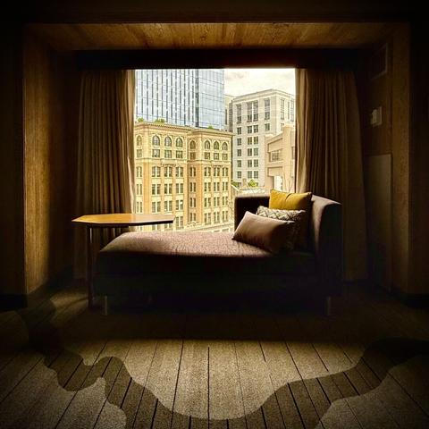Seating area next to a hotel window looking out at buildings in downtown Oakland, CA. The day is very gloomy, but it's still shining light into the otherwise dark hotel room
