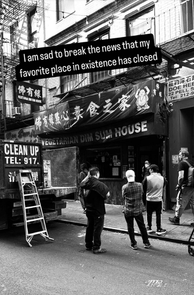 Image by @funerallucas (Instagram) as reposted to Facebook.  Description:  Black-and-white photo of a storefront on Pell St in Chinatown (NYC), with awnings in Chinese and English reading "VEGETARIAN DIM SUM HOUSE".  A dump truck is parked outside the storefront.  Somewhat obscured, a person wearing a mask may be carrying an item out of the restaurant.  Several pedestrians or laborers stand on the street and sidewalk, facing the restaurant (away from the camera), arms crossed.  Superimposed on the top of the image is the caption "I am sad to break the news that my favorite place in existence has closed".