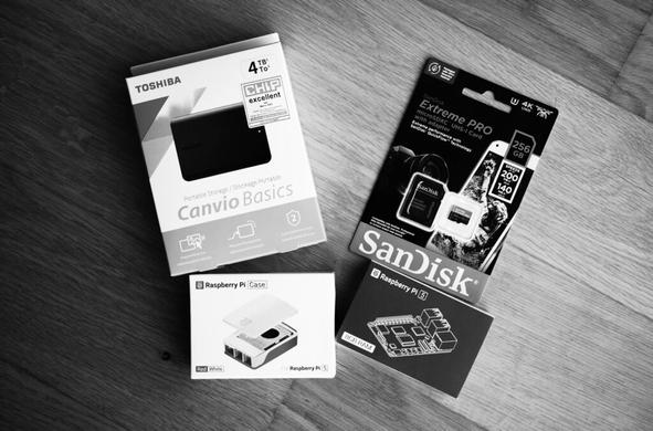 Foto von Verpackungen einer externen Festplatte, eines Raspberry PI, einer Micro-SD-Karte und eines Gehäuses für den Raspberry PI
