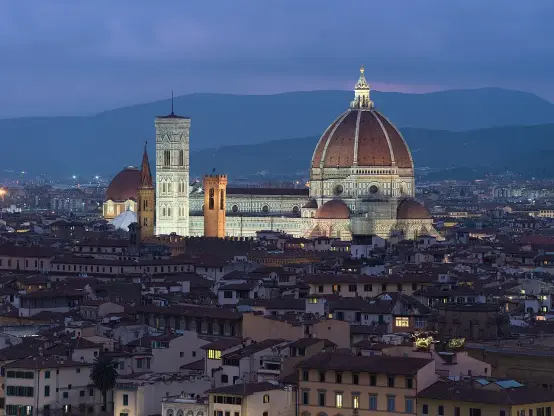 This image depicts the skyline of Florence, Italy, prominently featuring the Cathedral of Santa Maria del Fiore, known for its iconic dome designed by Brunelleschi. Nearby, you can also see the Giotto's Campanile and the Baptistery. The scene is illuminated at dusk, showcasing the historical architecture against a backdrop of the Tuscan landscape.

Image Credits: Wikimedia / Dllu / CC BY-SA 4.0