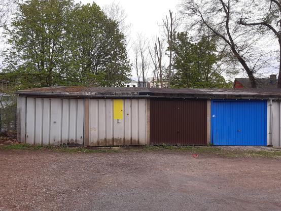 Blick auf einen Garagenhof. Zu sehen sind vier Garagentore in hellblaugrau, braun, blau