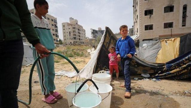 Uns infants omplen galledes amb aigua a la ciutat de Gaza, el 6 d'abril (Reuters/Mahmoud Issa)