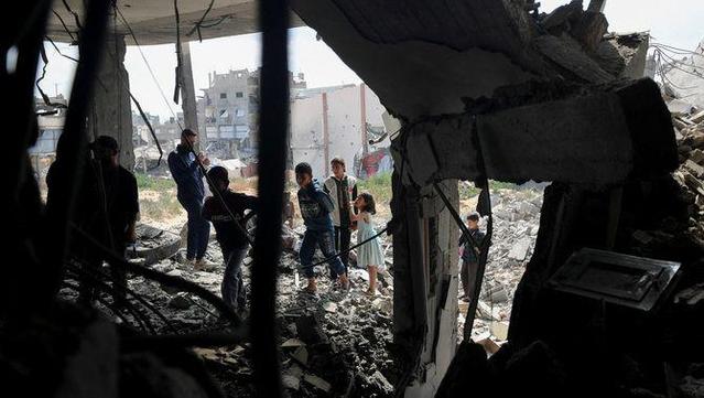 Adults i nens examinen la destrucció en un habitatge causada per un atac israelià (Reuters/Mahmoud Issa)