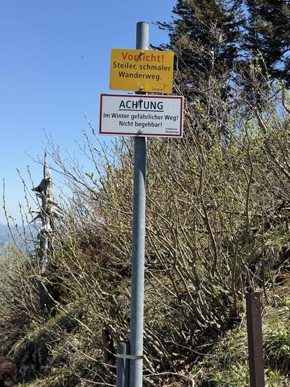 Ein Warnschild mit Aufschrift: Vorsicht! Steiler, schmaler Wanderweg. ACHTUNG, Im Winter gefährlicher Weg! Nicht begehbar!
A warning sign with the inscription: Caution! Steep, narrow hiking trail. ATTENTION, dangerous path in winter! Not passable!