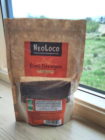 Pouch containing a black powder similar to ground coffee, but it is roasted chickpeas & malted barley. It is sitting on a windowsill, with a garden, blurred, in the background.

It is the produce Resistant Awakening from NeoLoco (Local culture, Total change), solar & organic artisans,

Recipe inspired from wartime periods where coffee was rare. This is today's coffee alternative from Normandy for climate fighters.