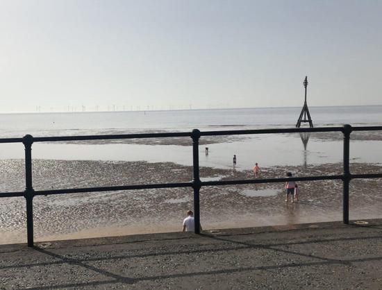 Photo of a beach with grey sky, children and railings