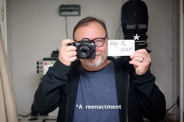 Mirror self-portrait with digital camera to demonstrate the addition of a date card in selfies for identifying film rolls/cameras.