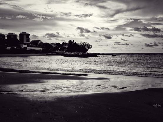 A humid, fiery sunset over the north eastern edge of Penang leaves the watery surfaces of the otherwise barren beach shimmering in a palette of silver tones