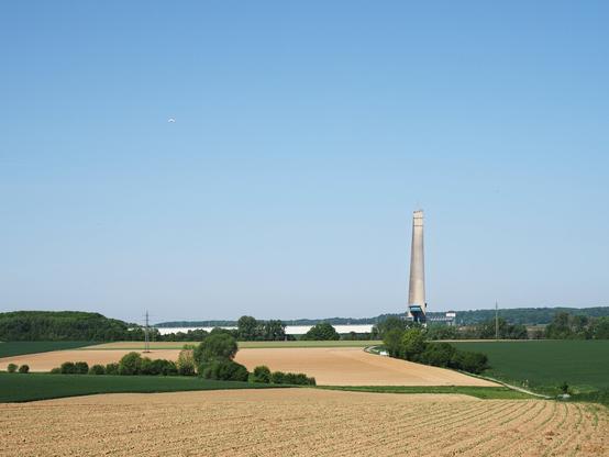 landscape with fields that have just been seeded, the upper control tower of the Ronquières inclined plane and a small tourist plane in flight