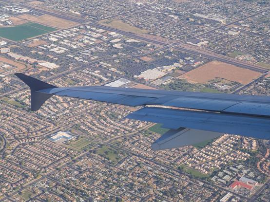 The wing of an airplane with a suburban area below