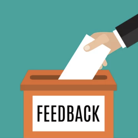 Image of hand inserting envelope into a box labeled feedback