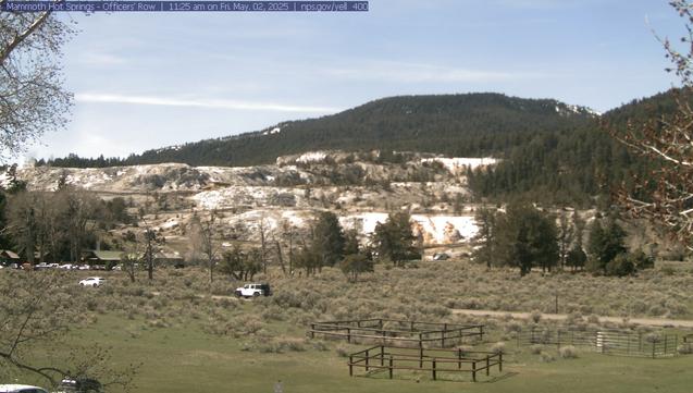Yellowstone is a place of change, and this view highlights a place where change is constant and evident—the travertine terraces of Mammoth Hot Springs. Terraces form when water rises through limestone, which then allows the water to carry high amounts of dissolved calcium carbonate. At the surface, carbon dioxide is released and the calcium carbonate is deposited, forming travertine, the chalky white rock of the terraces. In the foreground are the parade grounds for historic Fort Yellowstone—the focal point of daily life at the fort.