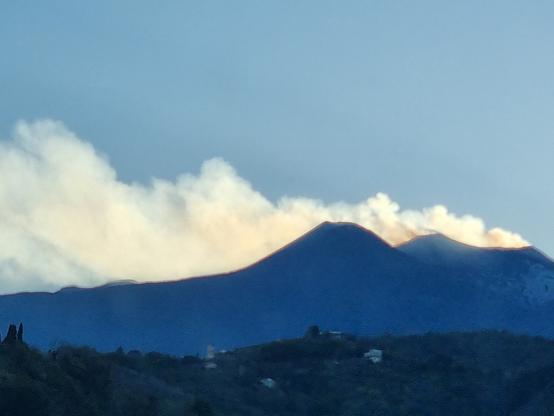 Etna al tramonto col fumo che si tinge di oro e arancio