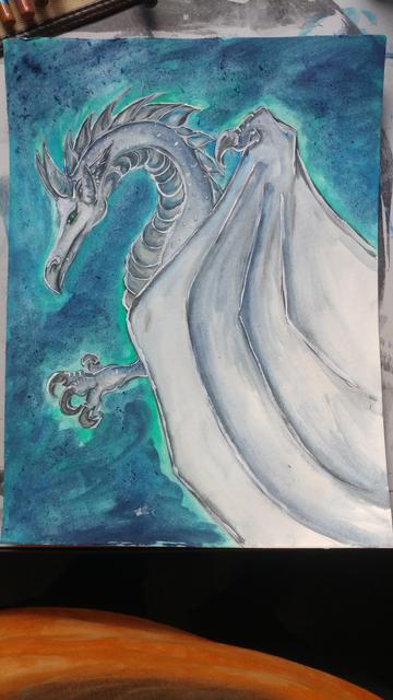 White and silver blue dragon on a green and blue background, painting on desk.