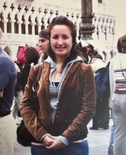 A teenage Caroline in jeans, a grey hoodie tee, and a brown velvet blazer.⁠