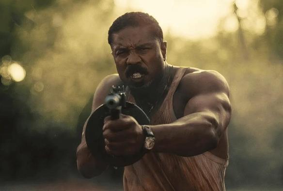 michael b jordan with a tommy gun shooting it into the camera