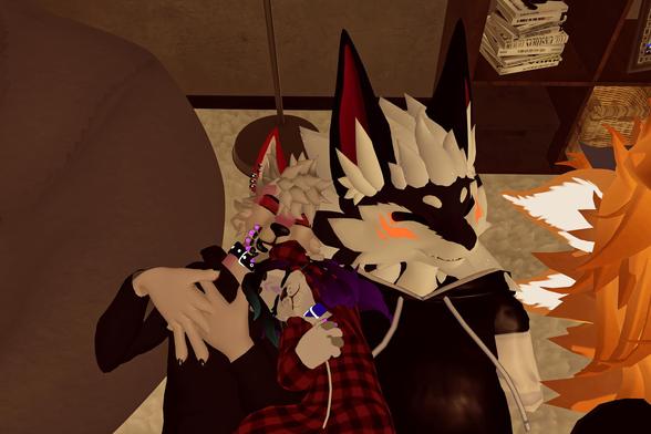 The image shows three anthropomorphic animal characters, likely foxes, cuddling together. The largest one, with black and white fur, is in the center and appears to be sleeping. A smaller fox with pink and white fur is nestled against its chest, also asleep. A third fox, with orange and yellow fur, is partially visible on the right side of the image. The scene suggests a close, familial bond and a sense of comfort and security.