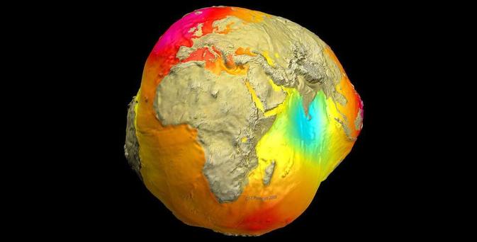 Distorted, potato-shaped rendering of the Earth showing variations in its gravitational field. Colors represent the strength of the gravity, with reds and yellows indicating stronger gravity and blues and purples indicating weaker gravity relative to a smooth, idealized Earth. Continents are faintly visible on the surface, providing geographical context to the gravitational anomalies.