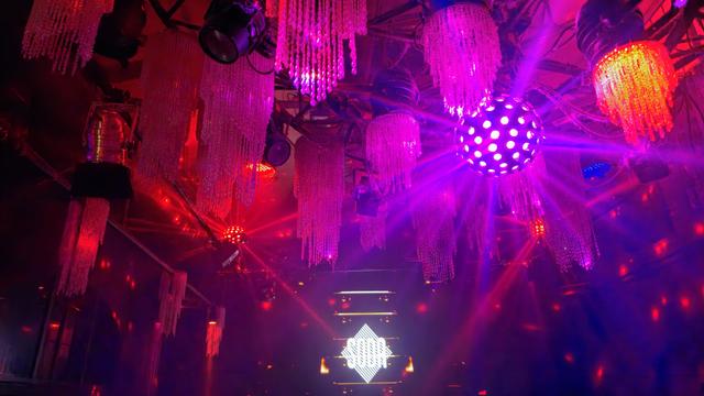 Foto von der Decke eines Floors im Soda Club, es hängen kronleuchterähnliche Lampen und Discokugeln herum, vorne ist das Logo des Soda zu sehen.