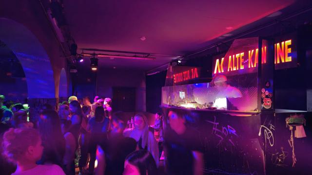 Foto vom Floor der alten Kantine, zu sehen ist das DJ-Pult und tanzende Menschen davor.