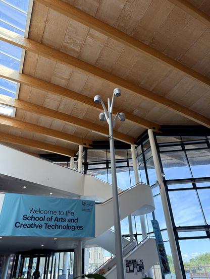 An atrium with a banner saying Welcome to the school of arts and creative technologies.