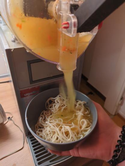 Gemüsebrühenslush wird in eine Schüssel voll Nudeln gefüllt