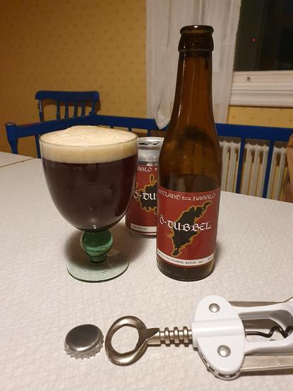 En kupa med mörkt öl med skumkrona bredvid Snausarves flaska.
