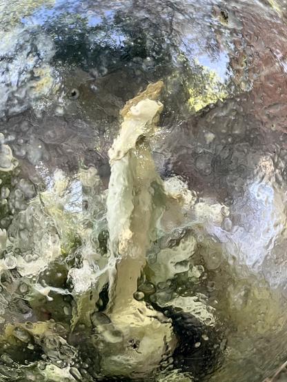 A blurry figure of a standing, hooded woman surrounded by reflections off the sphere’s surface.