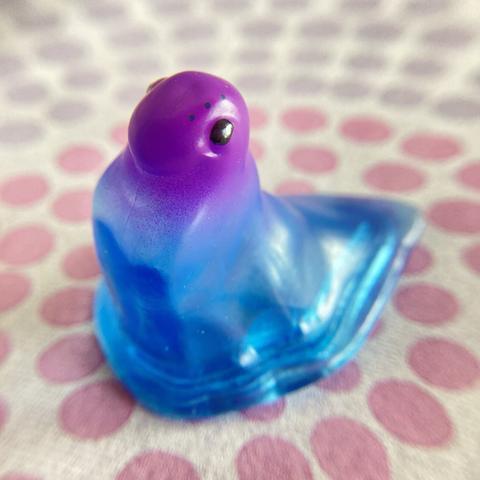 Murf auf einer rosa-lila gepunkteten Tischdecke, sein Kopf ist lila, sein Schleimwurm-Körper ist transparent blau.