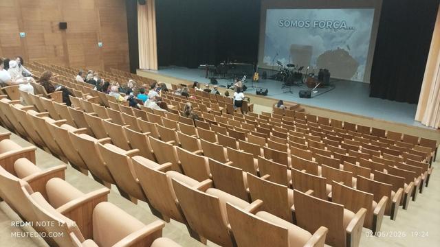 Teatro Poupex, Brasília. Cadeiras são em madeira clara e a plateia tem uma ótima inclinação. Palco já tem os instrumentos da banda que vai tocar.