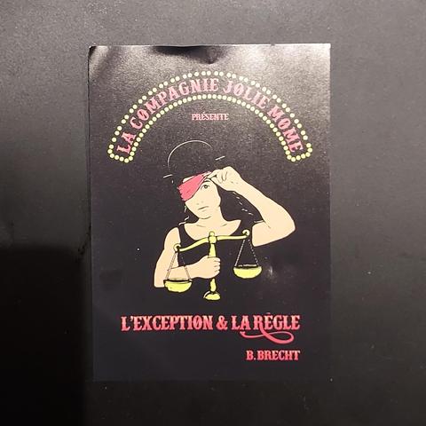recto du flier :
la justice tenant la balance d'or de la main droite et soulevant de la main gauche son bandea rouge.
Au dessus, comme une ancienne enseigne lumineuse de spectacle "LA COMPAGNIE JOLIE MÔME
présente"
et en dessous du personnage de la justice :
"L'EXCEPTION & LA RÈGLE
B. BRECHT"
Les lettres sont rouges, le fond de l'image est noire.