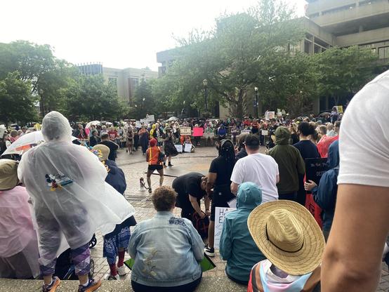 Woman in hat and dress introduces the next speaker.