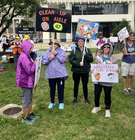 Group of women holding signs. One reads: "CLEAN - UP ON AISLE 47"