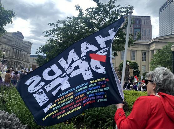 Woman with large "HANDS OFF" flag.