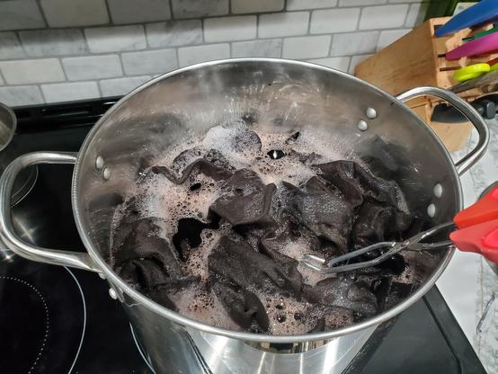 A very large pot full of fabric being dyed brown