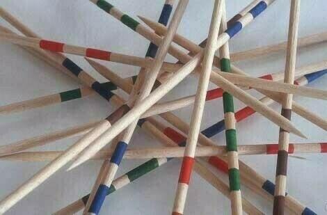 A jumble of wooden Mikado sticks with colored bands is scattered randomly on a surface.
