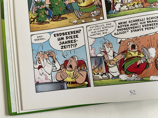 Miraculix steht an einem Topf, in dem der Zaubertrank gebraut wird. Er tippt sich an die Stirn und sagt, dass noch Erdbeeren fehlen würden.