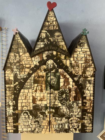 a sculpture of a church-like house with three naves and a large, currently closed, double-leaf gate. The façade of the house is covered with small tile-like picture cut-outs showing various female film stars from the 1930s to 1960s. Above the gate is a sign that reads 'Shrine of past Beauty'
