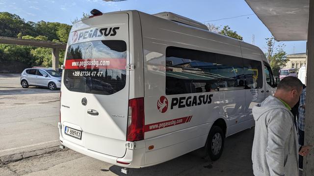 A white mini bus standing in a small bus terminal.
