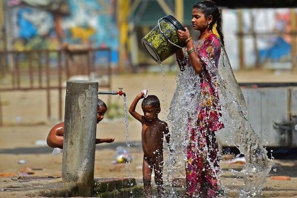Une femme et deux enfants s’aspergent d’eau en pleine rue.