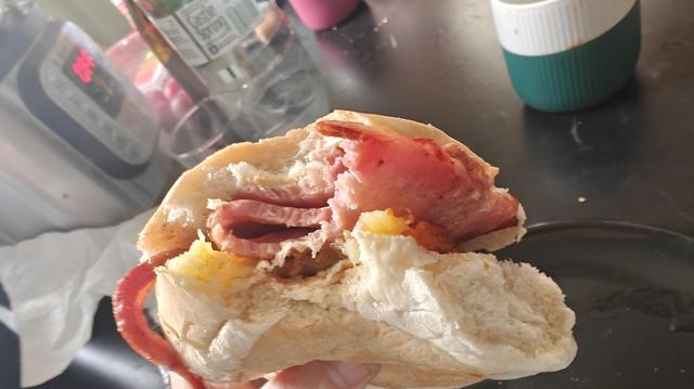 A white bread roll stuffed with bacon and crispy hash browns