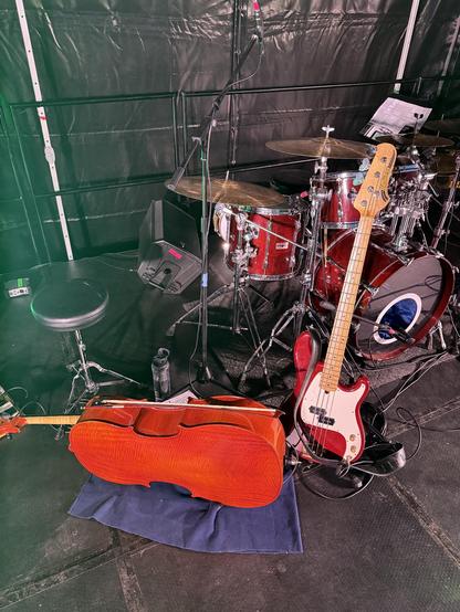 A cello, electric bass and drum kit on a stage