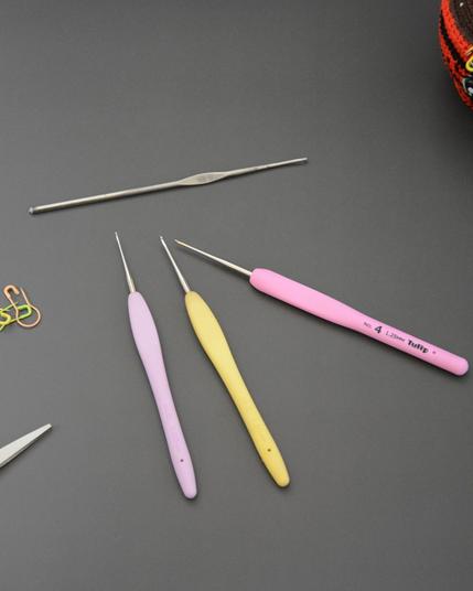 des crochets sont posés sur un fond gris, on devine des marqueurs et une paire de ciseau sur la droite