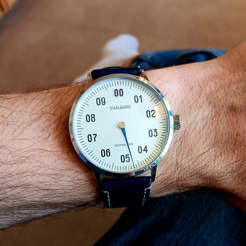 Decimal watch with a single hand showing the time as roughly 4:79.