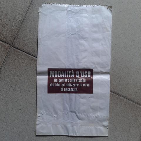 Nella fotografia, lo stesso sacchetto di carta.
Sulla parte posteriore la scritta: "Modalità d'uso. Da portare alla visione del film ed utilizzare in caso di necessità".