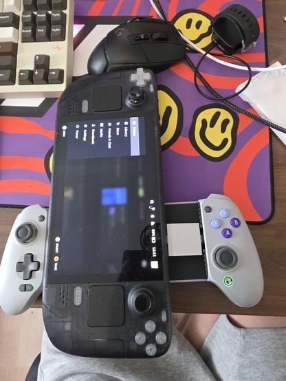 a steam deck lying vertically, attached to it via an usb-c extension is a controller intended for phones