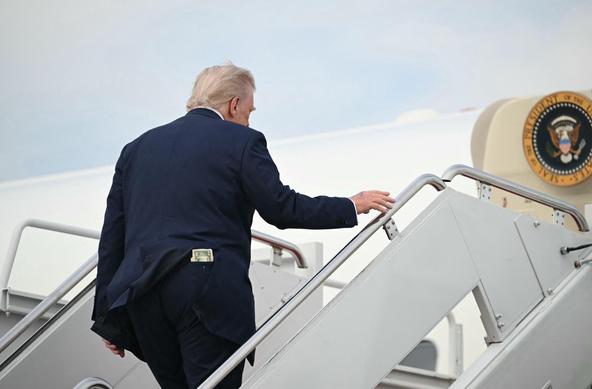 Trump in a suit is ascending the steps to Air Force One, with a presidential seal visible on the aircraft. A wodge of $50 bills is protruding from his back pocket.