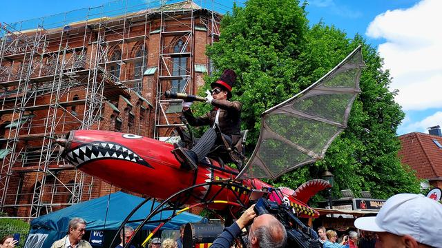 Fish-shaped winged Steampunk vehicle with driver in top hat and goggles