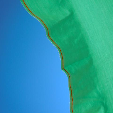 square picture, diagonally divided in two parts: on the left is a uniform blue surface, on the right is a green surface with folds and a curved edge along which a red line runs