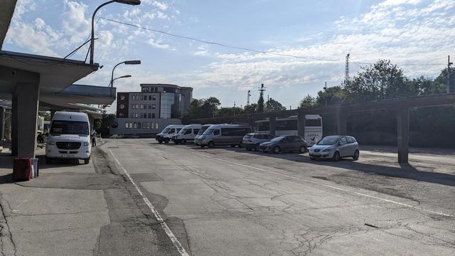 A small bus terminal with a couple of mini busses and one mainline bus.